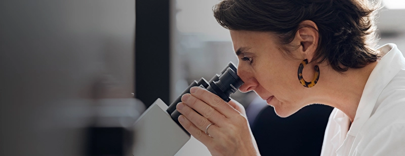 Laboratory researcher looking through a microscope.