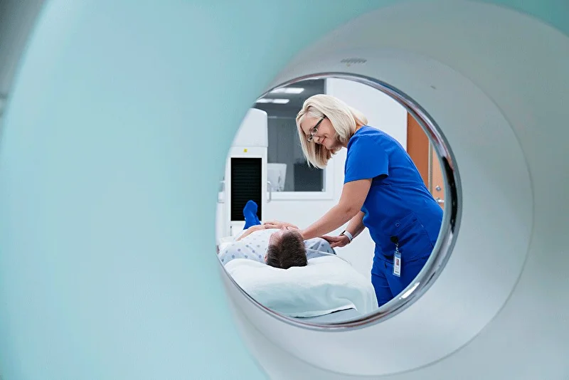 Nurse comforting patient that is on his way into the MRI machine