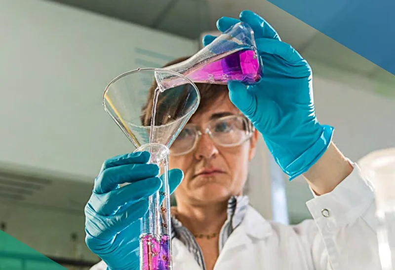 Female doctor pouring and mixing pink chemicals into a bottle