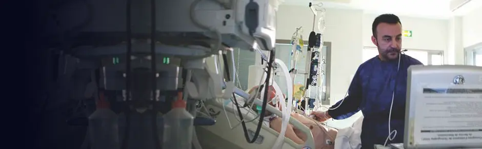 Patient in bed, with doctor looking at screen