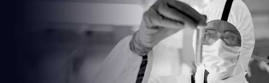 Man wearing biohazard suit looking at test tube